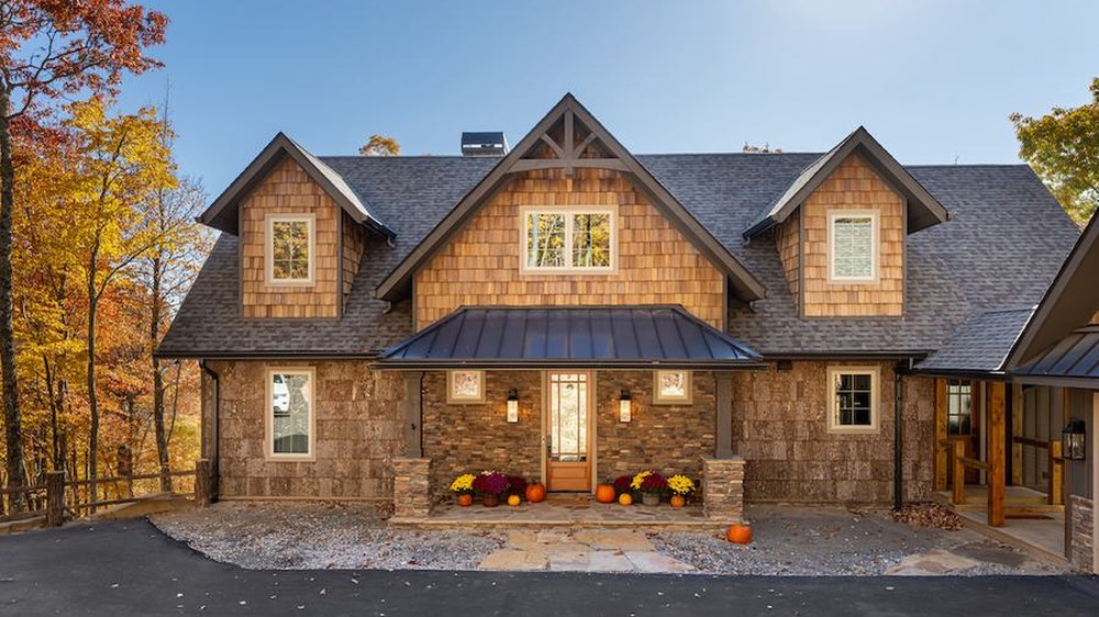 A Powell Construction custom mountain home with cedar shake siding and a stone base, set among fall foliage